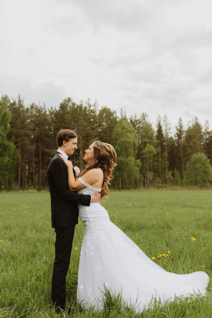 A happy bride and her groom standing in a field, in Sweden.